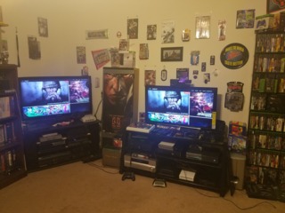 Still running dual TVs. OG Xbox, Xbox 360 w/HD DVD, Halo Ed Xbox One, Retron 5, Wii, and WiiU hooked up to the right side TV. Some gaming swag pinned to the wall.