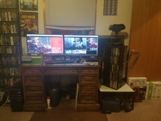 My desktop with some games waiting to be added to the inventory. PC games on the spiral rack to the right with a Virtual Boy on top. 